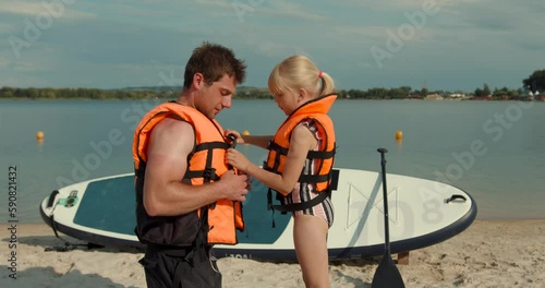 A father helping his daughter with her life jacket