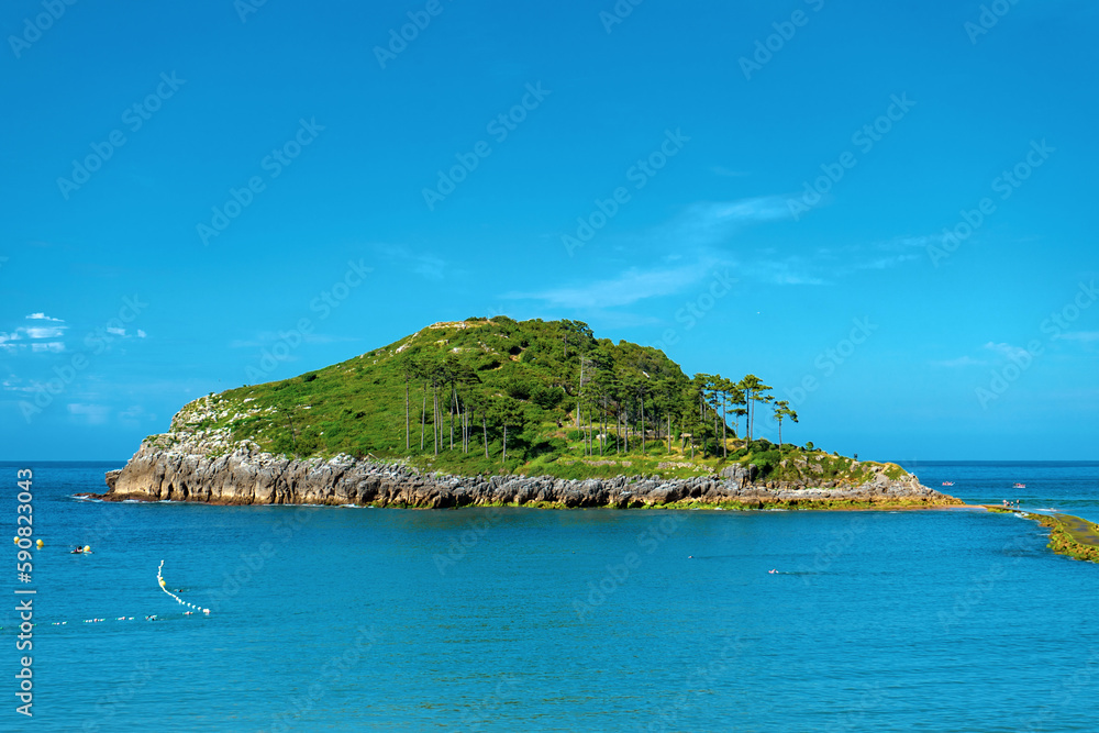 Naklejka premium San Nicolas Island in Lekeitio, Basque Country, Spain. Scenic coastal view with blue Atlantic water, rocky shoreline and lush green island landscape. Popular travel destination on the Bay of Biscay