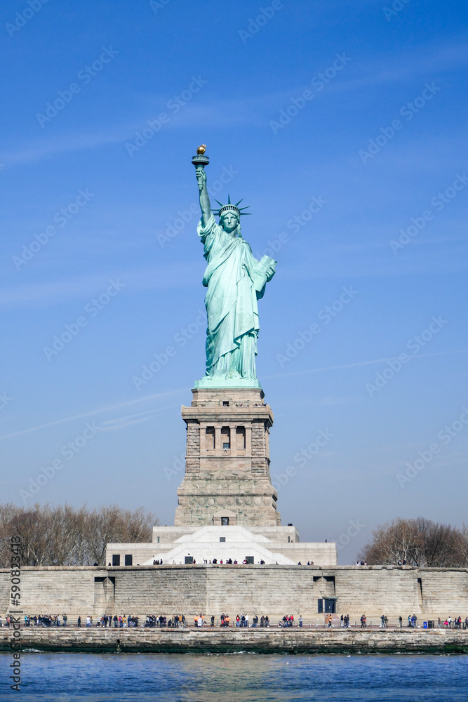 Fototapeta premium Statue of Liberty and base in full sun, clear blue sky. Looking head on at Statue from the Bay.