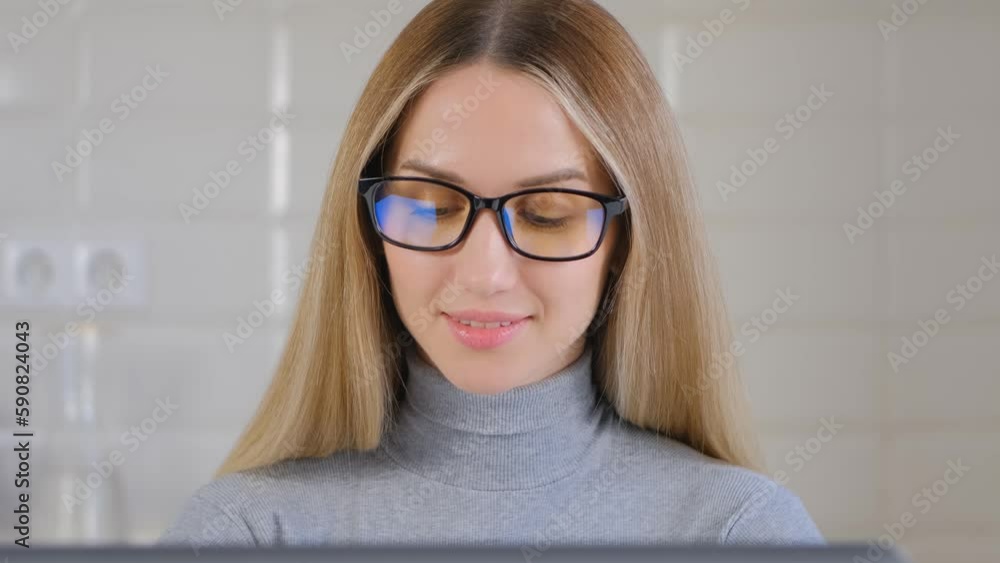 Beautiful blonde woman in glasses working on a computer at home. Portrait of pretty young female in glasses coding on a laptop Beautiful blonde woman in glasses working on a computer at home. Portrait of pretty young female in glasses coding on a laptop