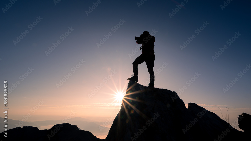 Silhouettes of tourists taking pictures on the mountain top and sunlight.