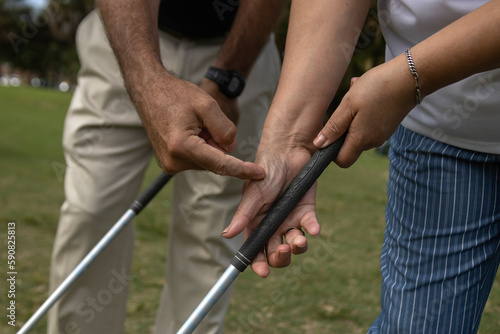 Golf instructor teaching how to a female apprentice to adjust her grip