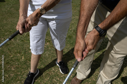 Golf instructor teaching how to a female apprentice to adjust her grip