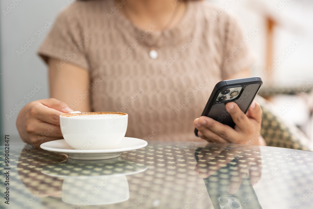 Illustration of woman's hand holding white mobile phone with blank screen and cup of coffee in cafe.