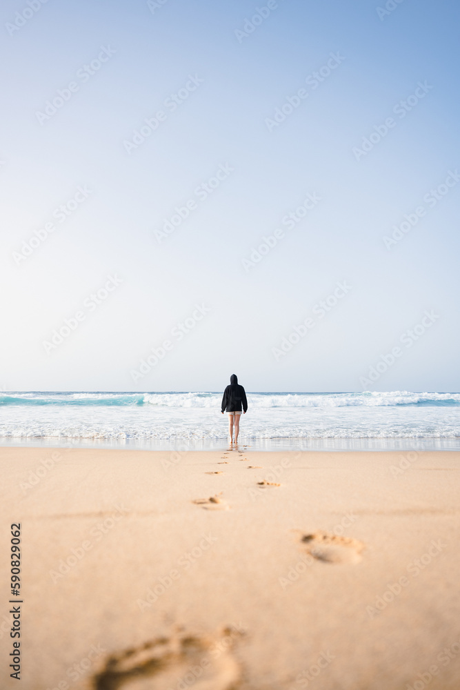 Stunning view a girl walking on the Cofete beach with her footprints on the sand in the foreground. Fuerteventura, Canary Islands.