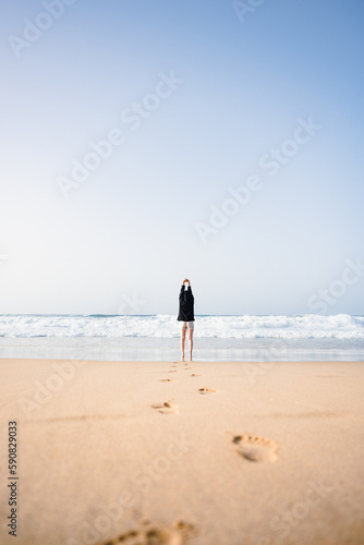 Stunning view a girl walking on the Cofete beach with her footprints on the sand in the foreground. Fuerteventura, Canary Islands.