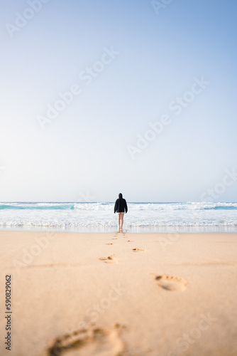 Obraz na płótnie Stunning view a girl walking on the Cofete beach with her footprints on the sand in the foreground. Fuerteventura, Canary Islands. w salonie