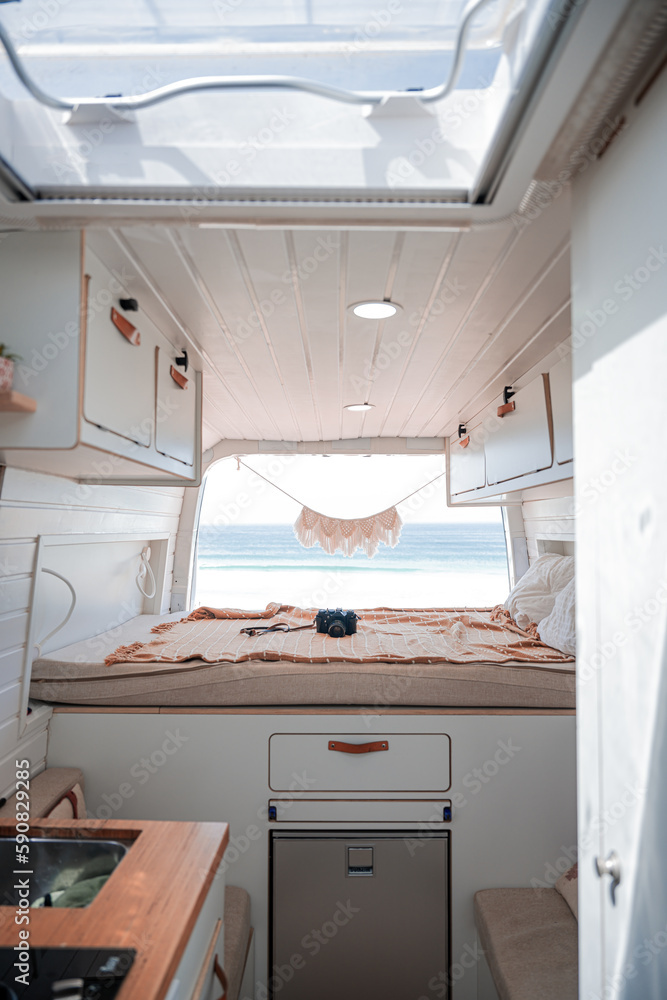 Stunning view of the interior of a van parked on a beach with the ocean in the distance. Life on the road concept, nomadic lifestyle. Fuerteventura, Canary Islands..