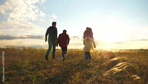 happy family. child father mother run sunset. girl boy parents cheerfully run green grass park.concept children run together joyfully summer. little daughter son happy together. game active child