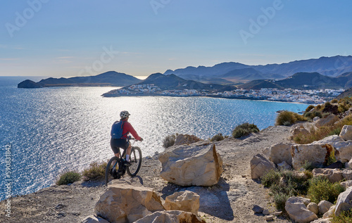 nice senior woman cycling with her electric mountain bike in the volcanic nature park of Cabo de Gata, Costa del Sol, Andalusia, Spain