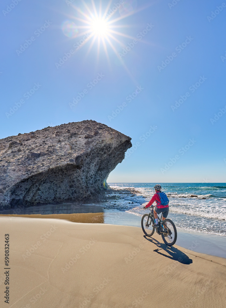 Fototapeta premium nice senior woman cycling with her electric mountain bike in the volcanic nature park of Cabo de Gata, Costa del Sol, Andalusia, Spain