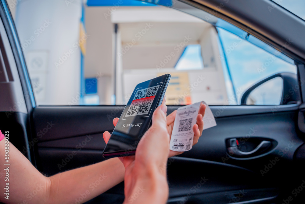 Woman using contactless payment by mobile phone with QR code at car filling station Woman using contactless payment by mobile phone with QR code at car filling station