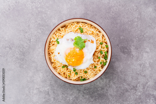 Instant noodles or ramen with minced pork and boiled egg in white bowl on the table with copy space - top view