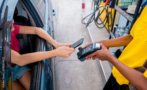 Woman using contactless payment by mobile phone with QR code at car filling station