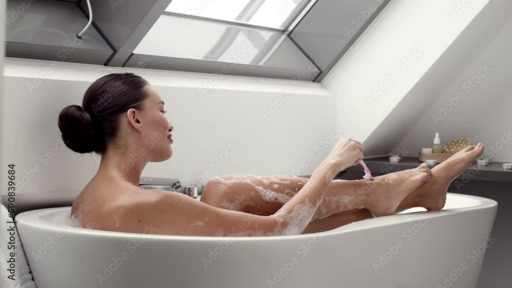 Domestic skin care. Young pretty lady taking bath at hove and shaving her legs, enjoying beauty procedures, slow motion Domestic skin care. Young pretty lady taking bath at hove and shaving her legs, enjoying beauty procedures, slow motion