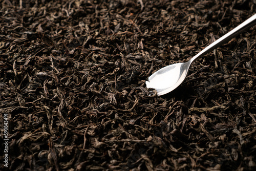 Fotografie A teaspoon scooping up black loose-leaf tea and being examined in detail
