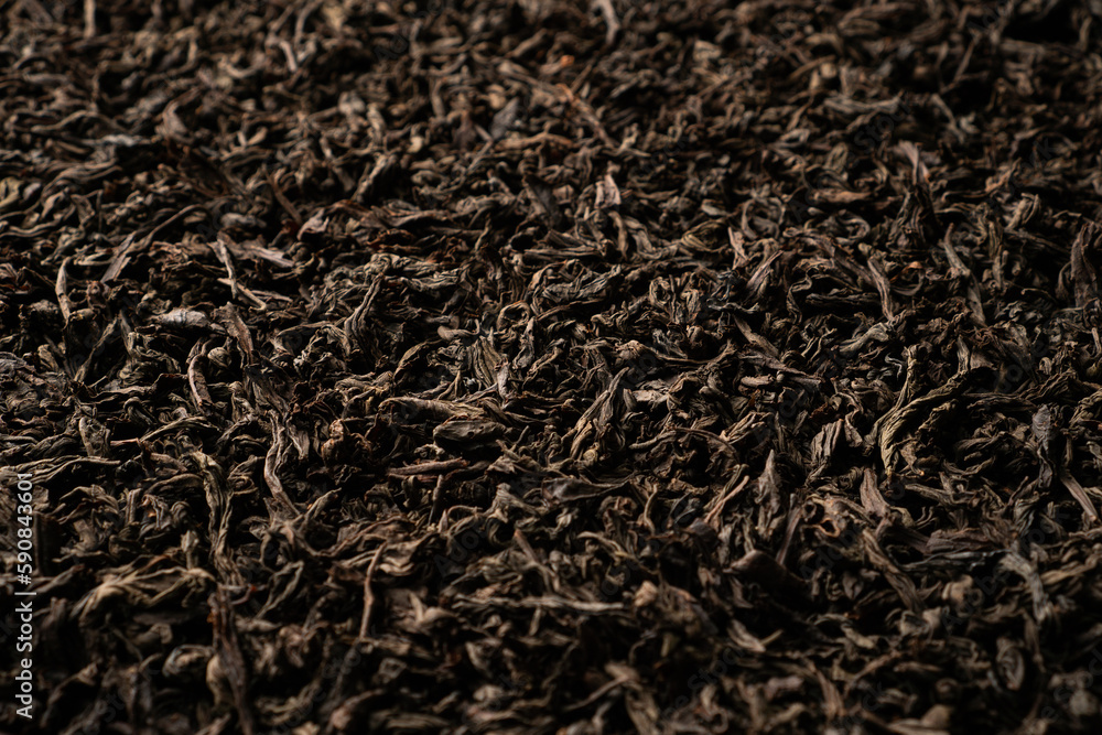 Background of black loose-leaf tea. Close up, angled view