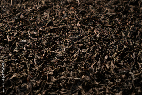 Background of black loose-leaf tea. Close up, angled view