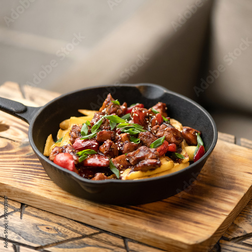 Potatoes with stewed meat in sauce. Meat in sauce. Dish in portion pan on wooden board. Lunch at home. Side view. Copy space. Light gray background. 