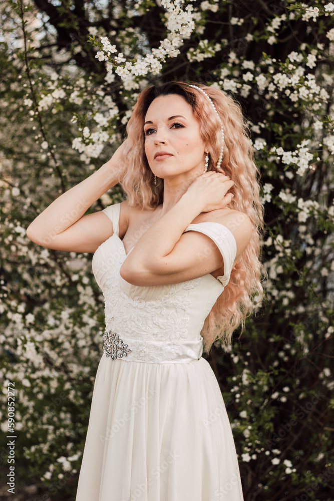 A beautiful woman in a spring garden near cherry blossoms. Flowering garden A beautiful woman in a spring garden near cherry blossoms. Flowering garden
