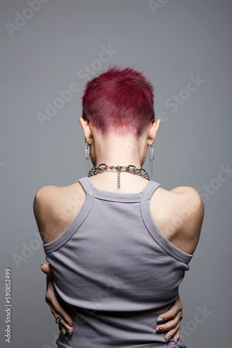 Female back. Young beautiful woman with painted short hair and a chain necklace