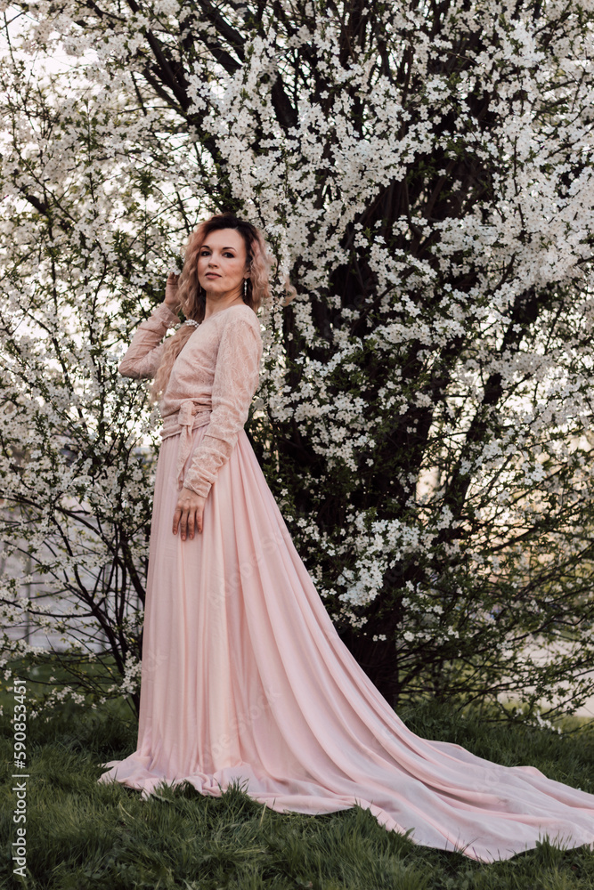 A beautiful woman in a spring garden near cherry blossoms. Flowering garden