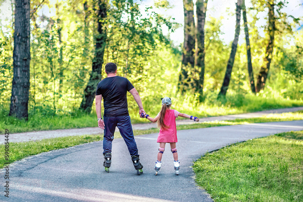 Fototapeta premium A father teaching his daughter roller skating in a park on summer day. Happy week-end. Father's day.