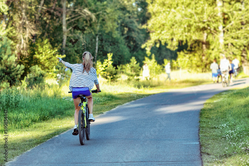 A young woman riding a bicycle in a park in summer.