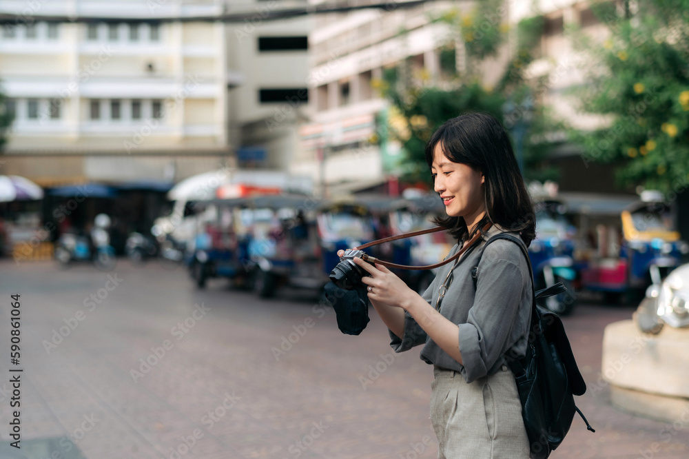 Young Asian woman backpack traveler using digital compact camera, enjoying street cultural local place and smile. Traveler checking out side streets. Young Asian woman backpack traveler using digital compact camera, enjoying street cultural local place and smile. Traveler checking out side streets.
