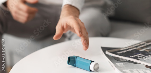 Man taking inhaler from table, closeup