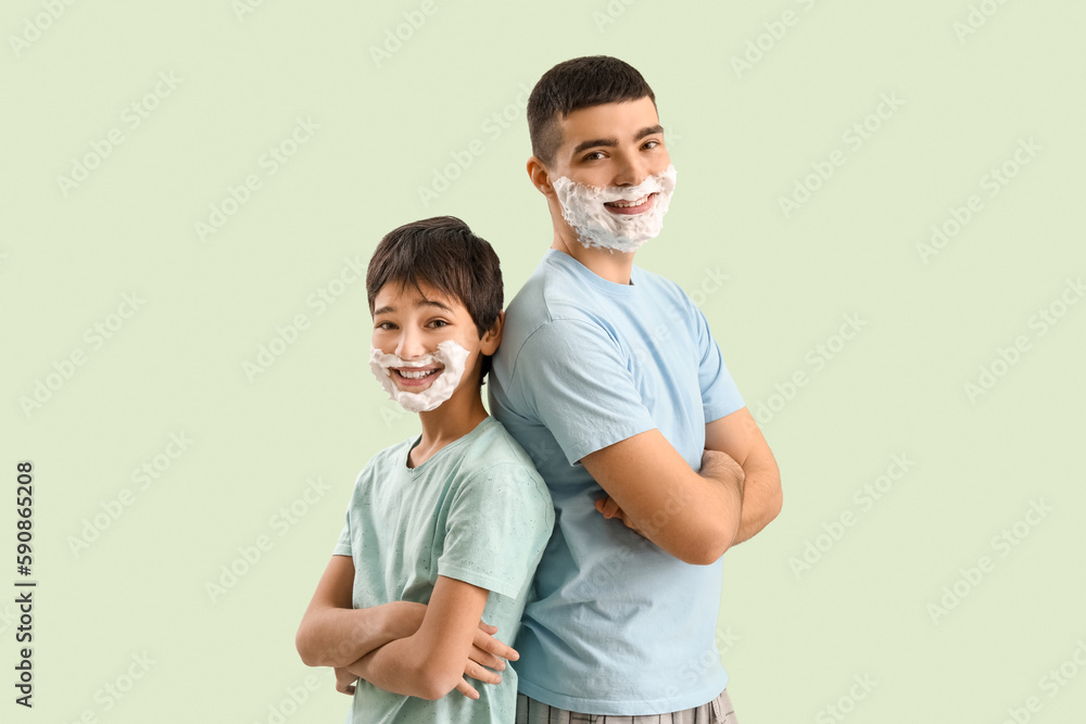 Man and his little son with shaving foam on faces against light color background Man and his little son with shaving foam on faces against light color background