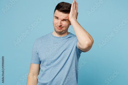 Young sad misaken puzzled embarrassed caucasian european man wear casual t-shirt look camera hold scratch head isolated on plain pastel light blue cyan background studio portrait. Lifestyle concept.