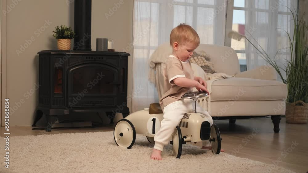 Happy child at home. Little toddler boy driving big vintage toy car and having fun. Smiling kid playing at home. Baby boy playing with toy in living room indoors Happy child at home. Little toddler boy driving big vintage toy car and having fun. Smiling kid playing at home. Baby boy playing with toy in living room indoors
