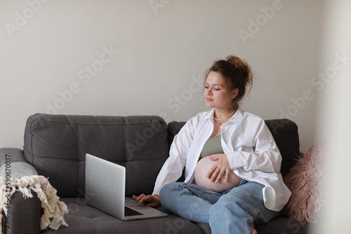 Attractive pregnant young lady working remotely online from home office. Close up woman hands on laptop with big belly advanced pregnancy. selective focus.
