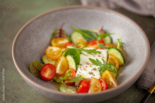 Easy greek salad of fresh cucumber, tomato, arugula, feta cheese with olive oil. Healthy food.