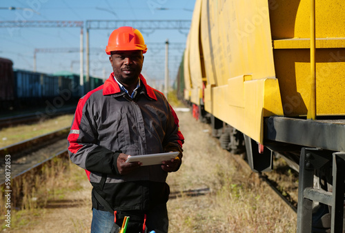 Railroad man in uniform and red hard hat with computer photo