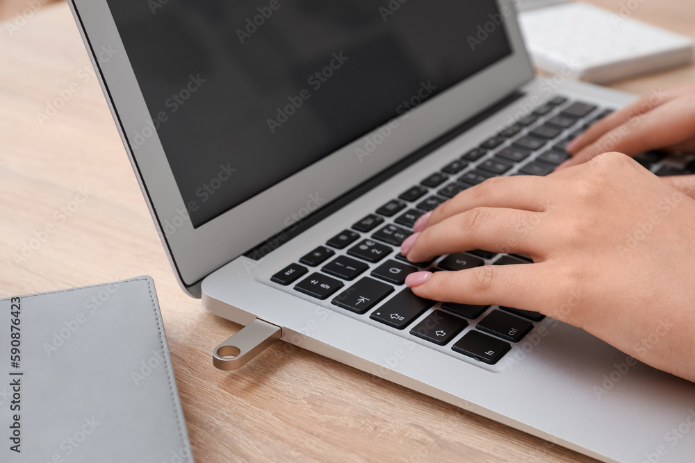 Female hands with modern laptop, USB flash drive and book on wooden table, closeup Female hands with modern laptop, USB flash drive and book on wooden table, closeup