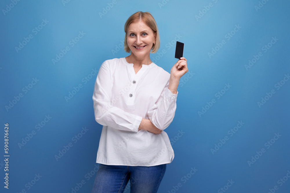 pensive slim blondie middle-aged woman in a white blouse holding a plastic card for shopping pensive slim blondie middle-aged woman in a white blouse holding a plastic card for shopping