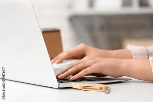 Woman with USB flash drive and modern laptop at light table, closeup