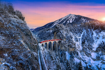 Landscape of Train passing through famous mountain in Filisur, Switzerland. Landwasser Viaduct world heritage with train express in Swiss Alps snow winter scenery.