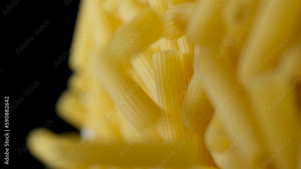 Flying wheat pasta Rigatoni in the form of tubes fall from top to bottom, close-up, slow motion shooting. Flying wheat pasta Rigatoni in the form of tubes fall from top to bottom, close-up, slow motion shooting.