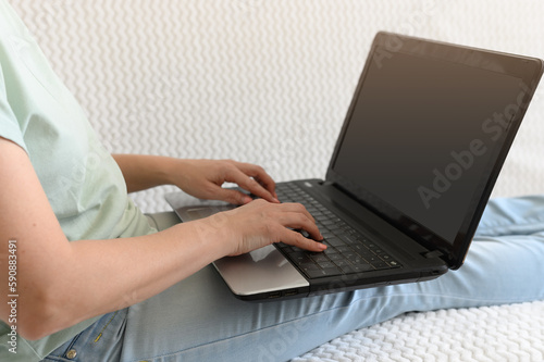 Young girl in blue jeans on the sofa with a laptop. With window light.