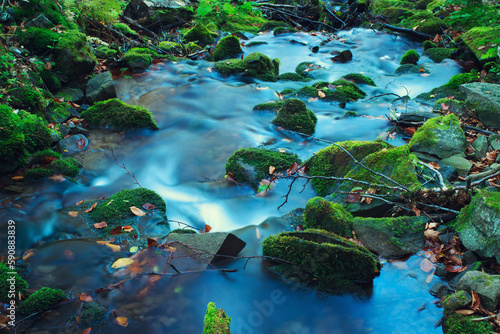 Mountain water stream on stones with moss. Long exposure effect.