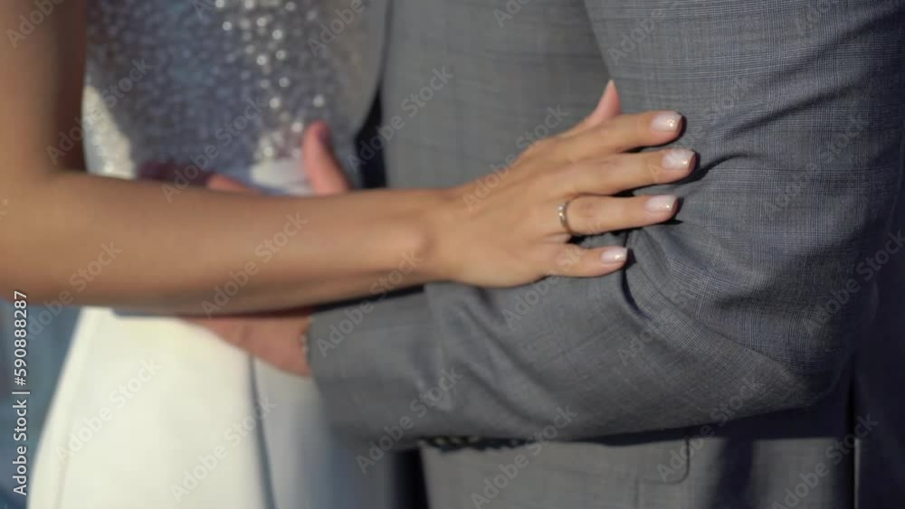 The bride and groom are hugging. A young couple in love in a white wedding dress and a grey classic suit. Husband and wife - relationship, family, wedding anniversary or honeymoon. The bride and groom are hugging. A young couple in love in a white wedding dress and a grey classic suit. Husband and wife - relationship, family, wedding anniversary or honeymoon.