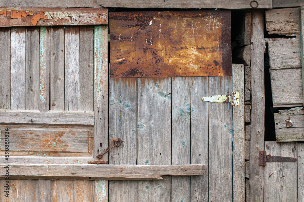 The wall of an old wooden barn built from scrap materials. The texture of old boards. 