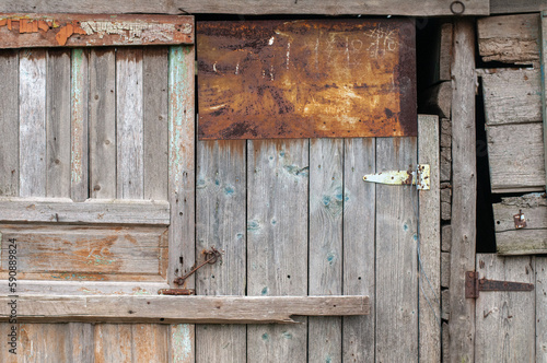 The wall of an old wooden barn built from scrap materials. The texture of old boards.  © Олександр Маляренко