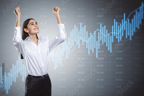 Happy young businesswoman with glowing candlestick forex chart on gray background with index. Trade, stock and global finance concept. Double exposure.