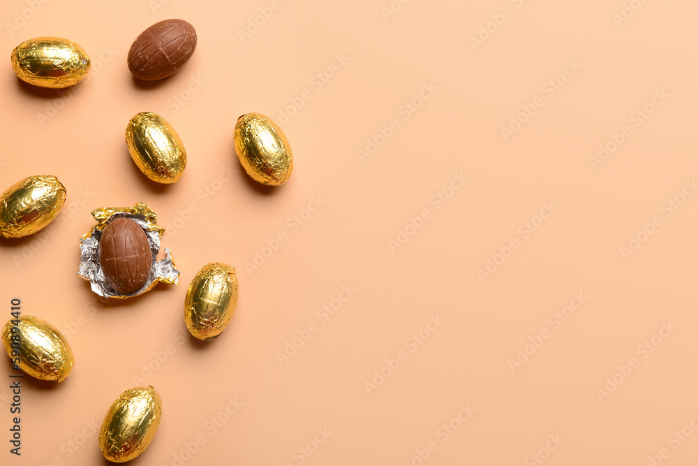 Chocolate Easter eggs in golden foil on beige background Chocolate Easter eggs in golden foil on beige background