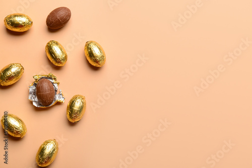 Chocolate Easter eggs in golden foil on beige background