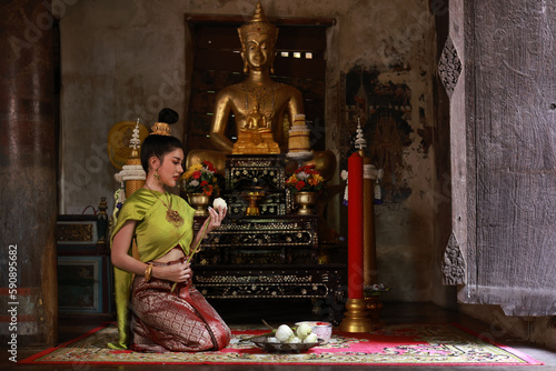 Beautiful Asia woman with Thai Traditional dress prepare lotus flower for make merit on Buddhist holy day © naraichal